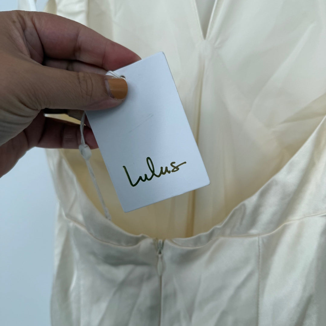 Hand holding a Lulus tag on a white garment