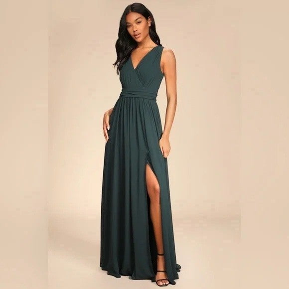 Woman wearing a dark green evening gown with a slit on a beige background