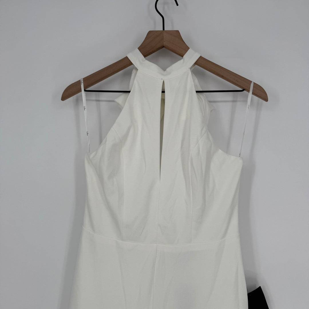 White dress on a wooden hanger against a plain background