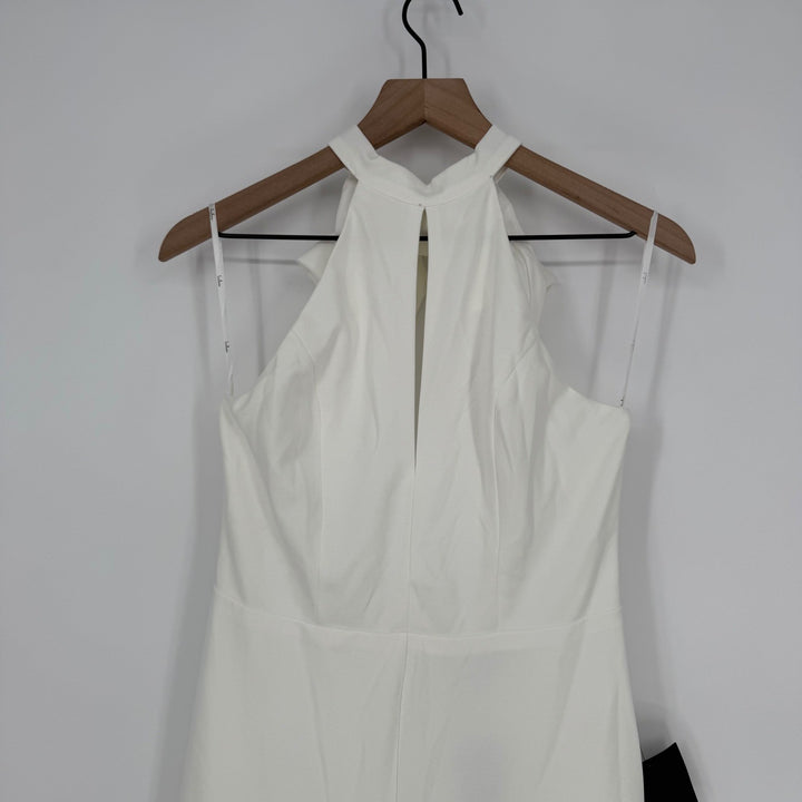White dress on a wooden hanger against a plain background
