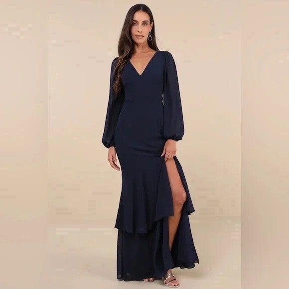 Woman wearing a navy blue evening gown with a slit on a beige background