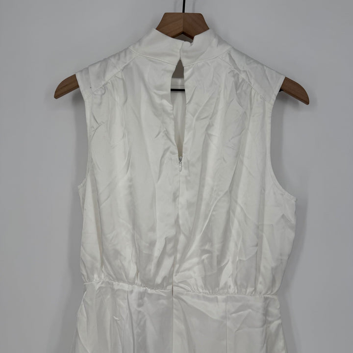 White sleeveless dress on a wooden hanger against a plain background