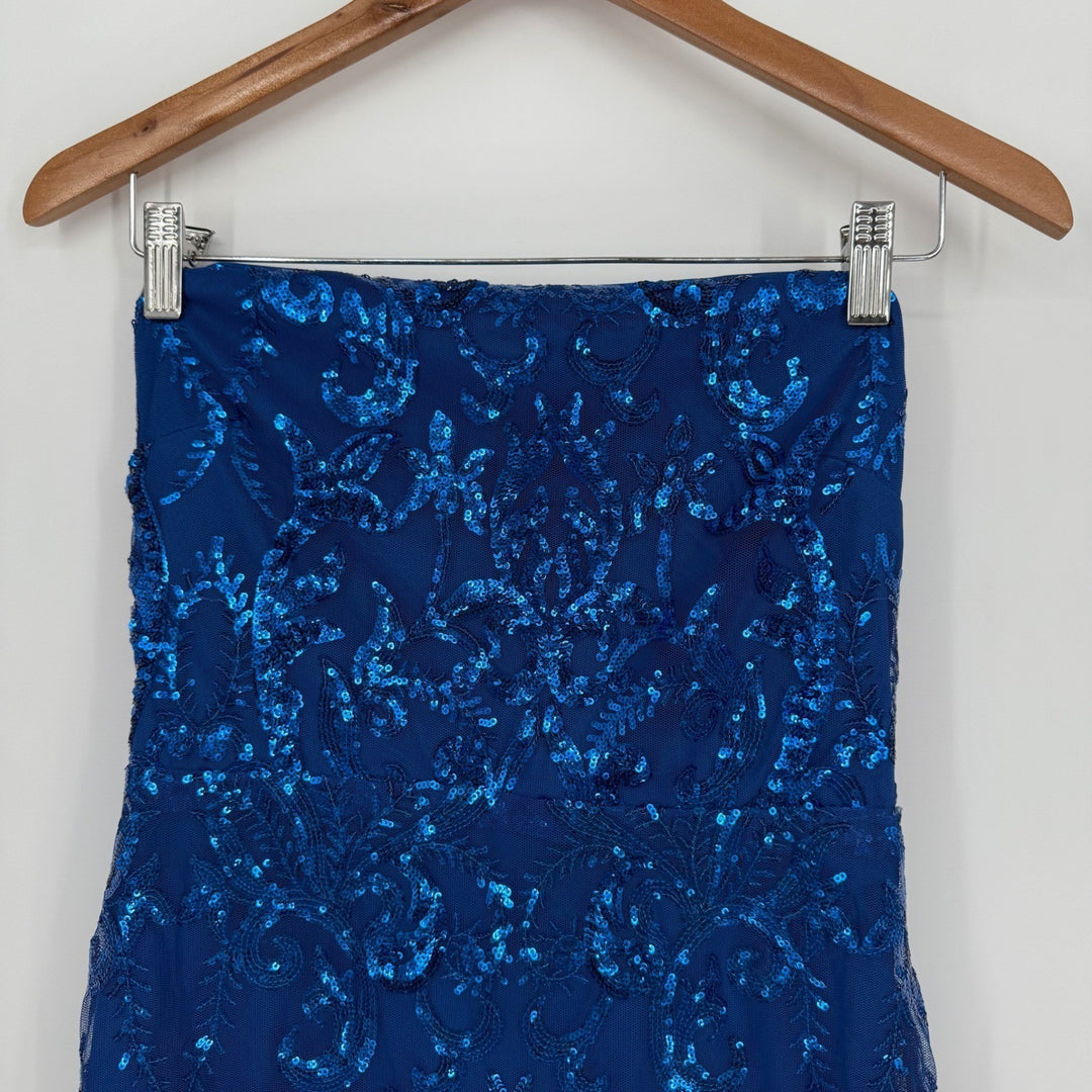 Blue sequin dress on a wooden hanger against a white background