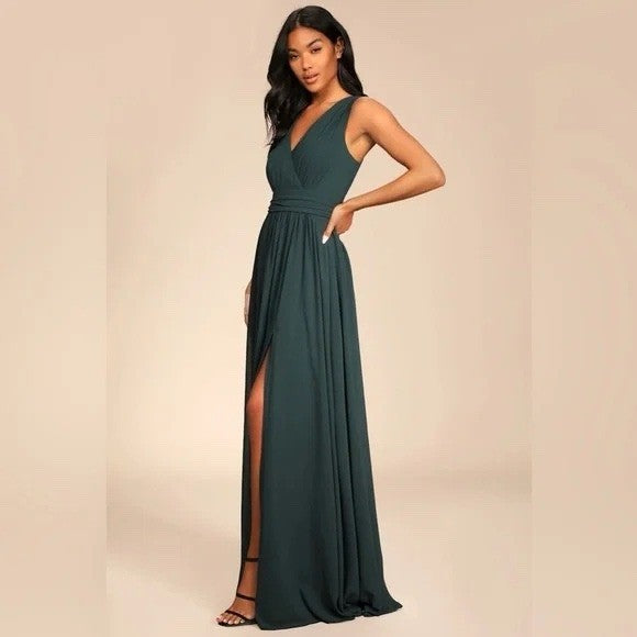 Woman wearing a dark green evening gown with a slit on a beige background