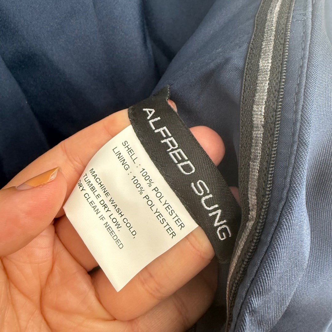 Hand holding a label on a piece of clothing with 'Alfred Sung' branding.
