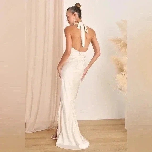Woman wearing a white evening gown with a high slit, standing against a neutral background.