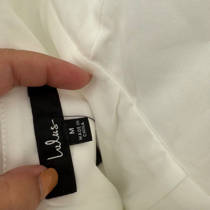 Close-up of a white garment with a label held by a hand.