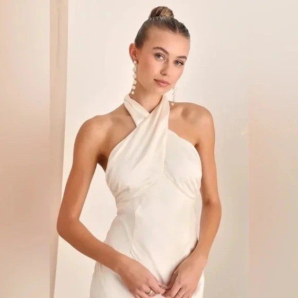 Woman wearing a white halter neck dress against a plain background