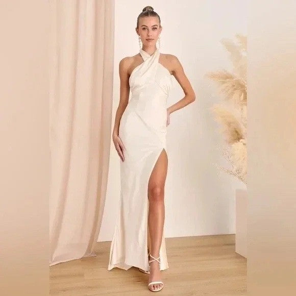 Woman wearing a white halter neck gown with a high slit, standing against a neutral background.