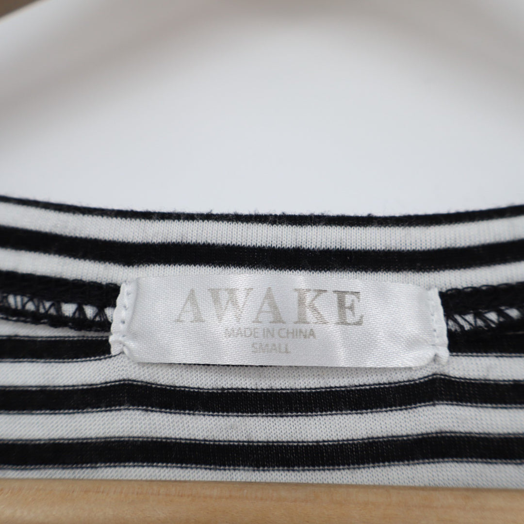 Close-up of a black and white striped shirt with 'AWAKE' label on a wooden surface