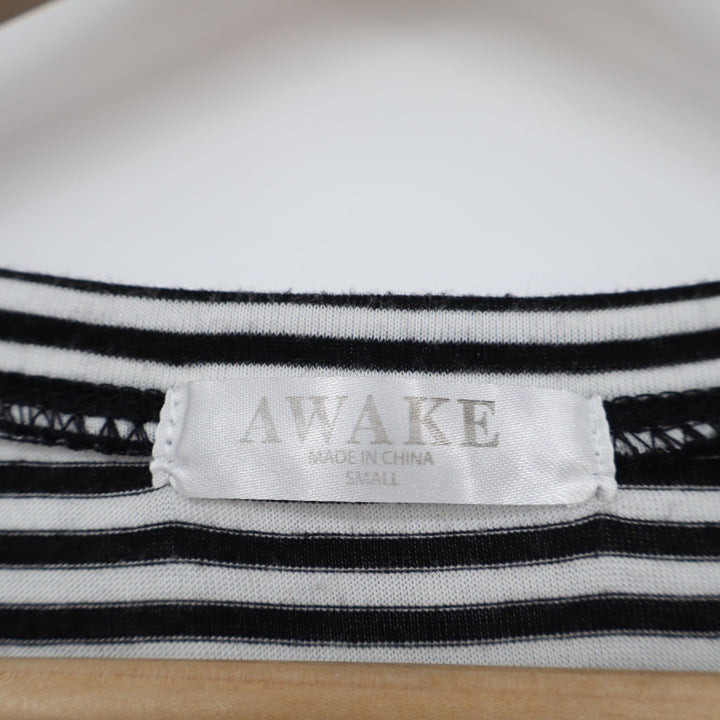 Close-up of a black and white striped shirt with 'AWAKE' label on a wooden surface
