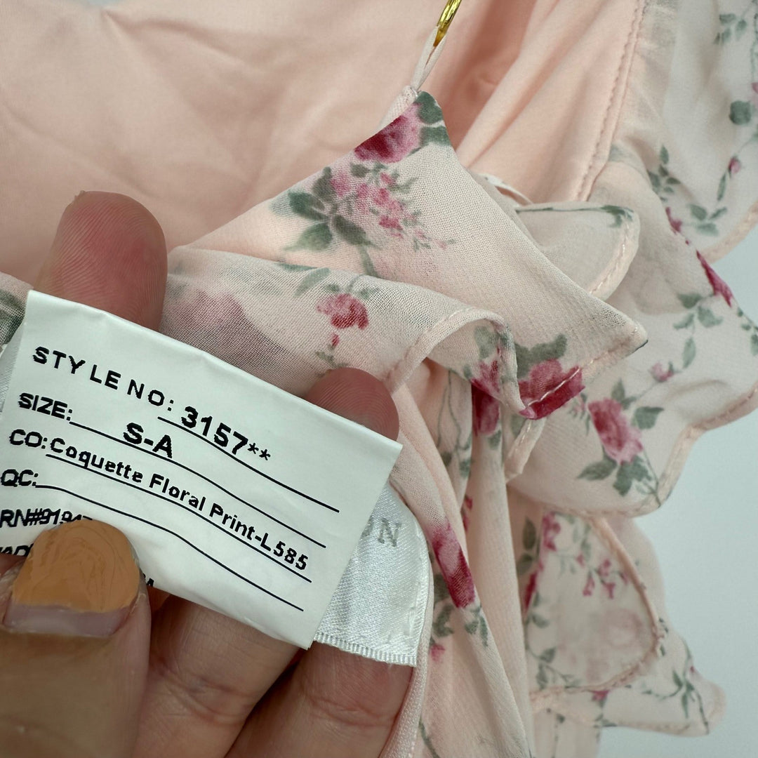 Floral-patterned garment with a label held by a hand