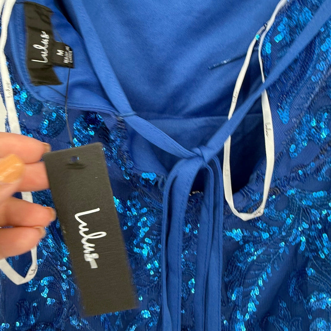 Blue sequin garment with a visible brand tag on a plain background