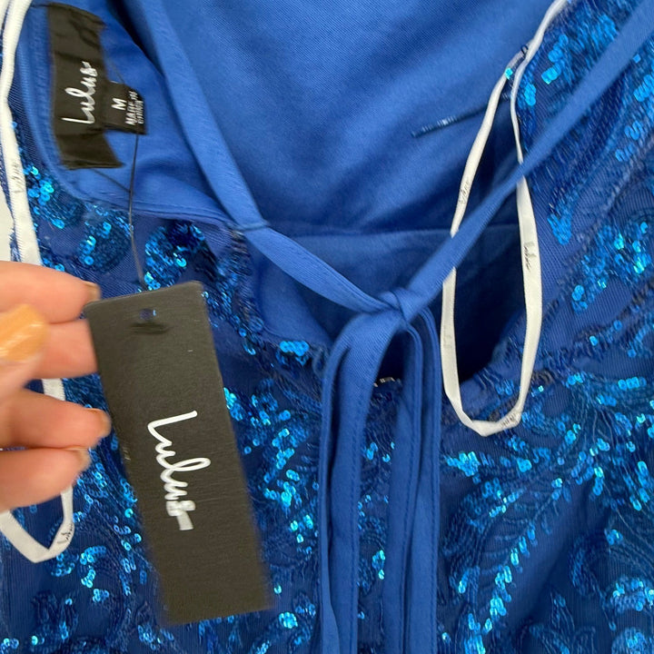 Blue sequin garment with a visible brand tag on a plain background