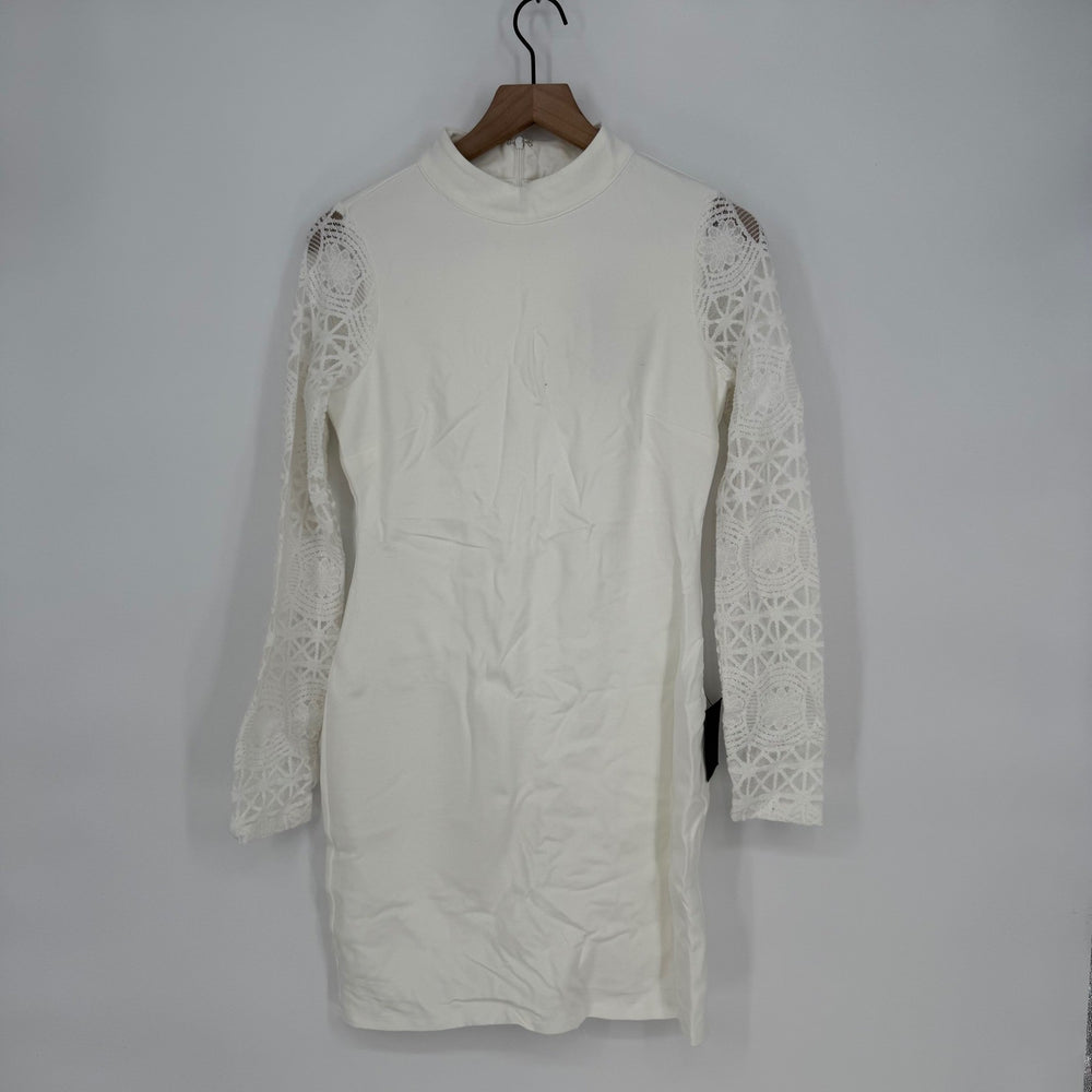 White dress with lace sleeves on a hanger against a plain background
