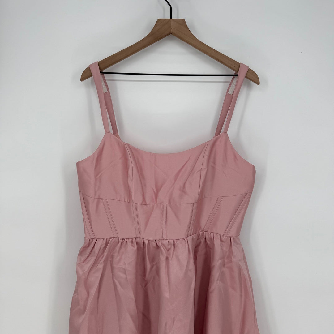 Pink dress on a wooden hanger against a white background