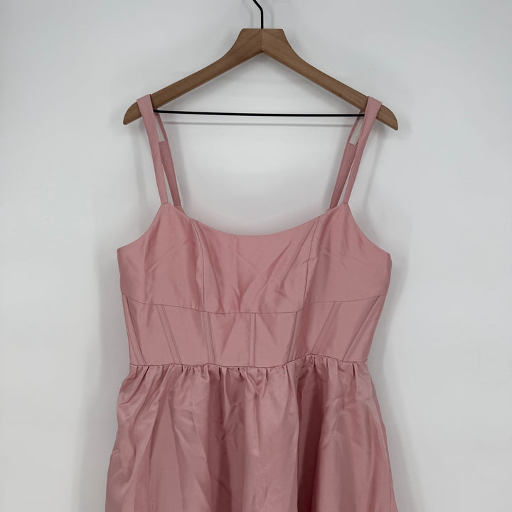 Pink dress on a wooden hanger against a white background