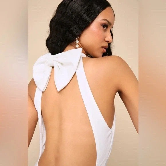 Woman wearing a white jumpsuit with a bow detail on a beige background