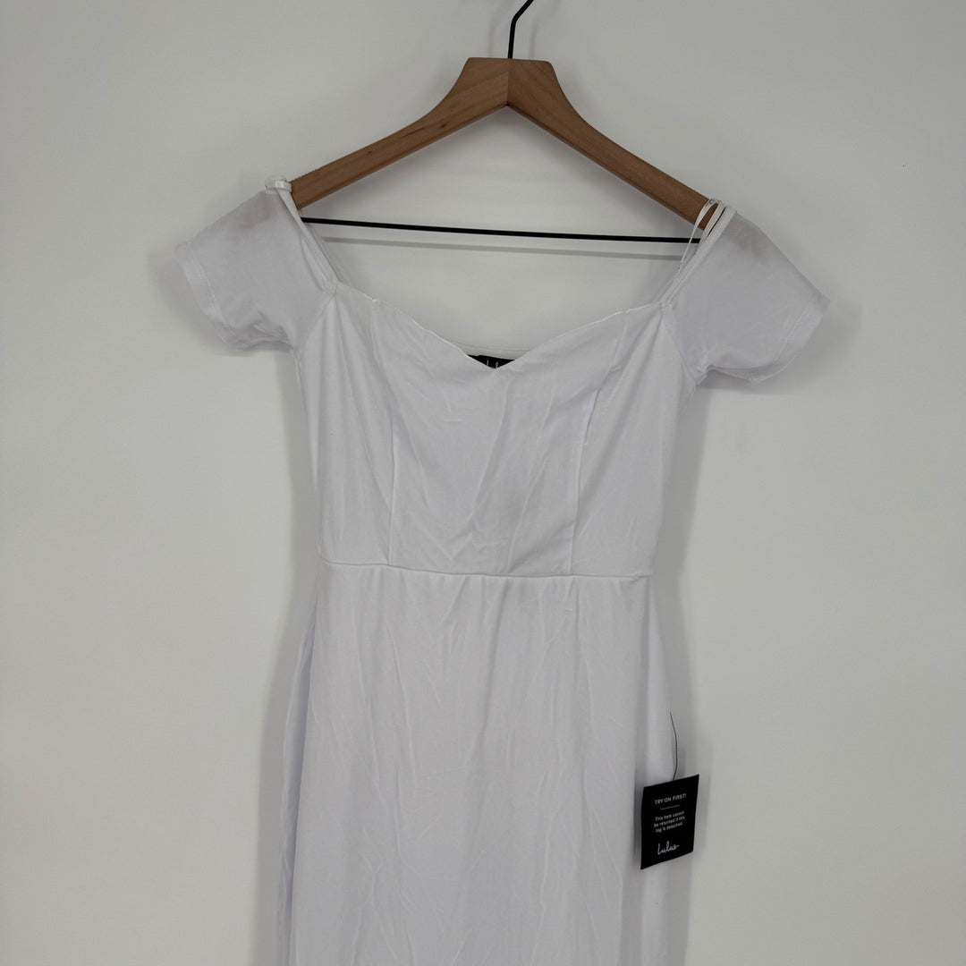 White dress on a wooden hanger against a white background