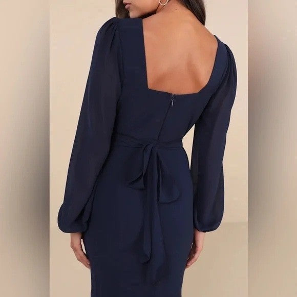 Navy blue dress with long sleeves and open back on a neutral background