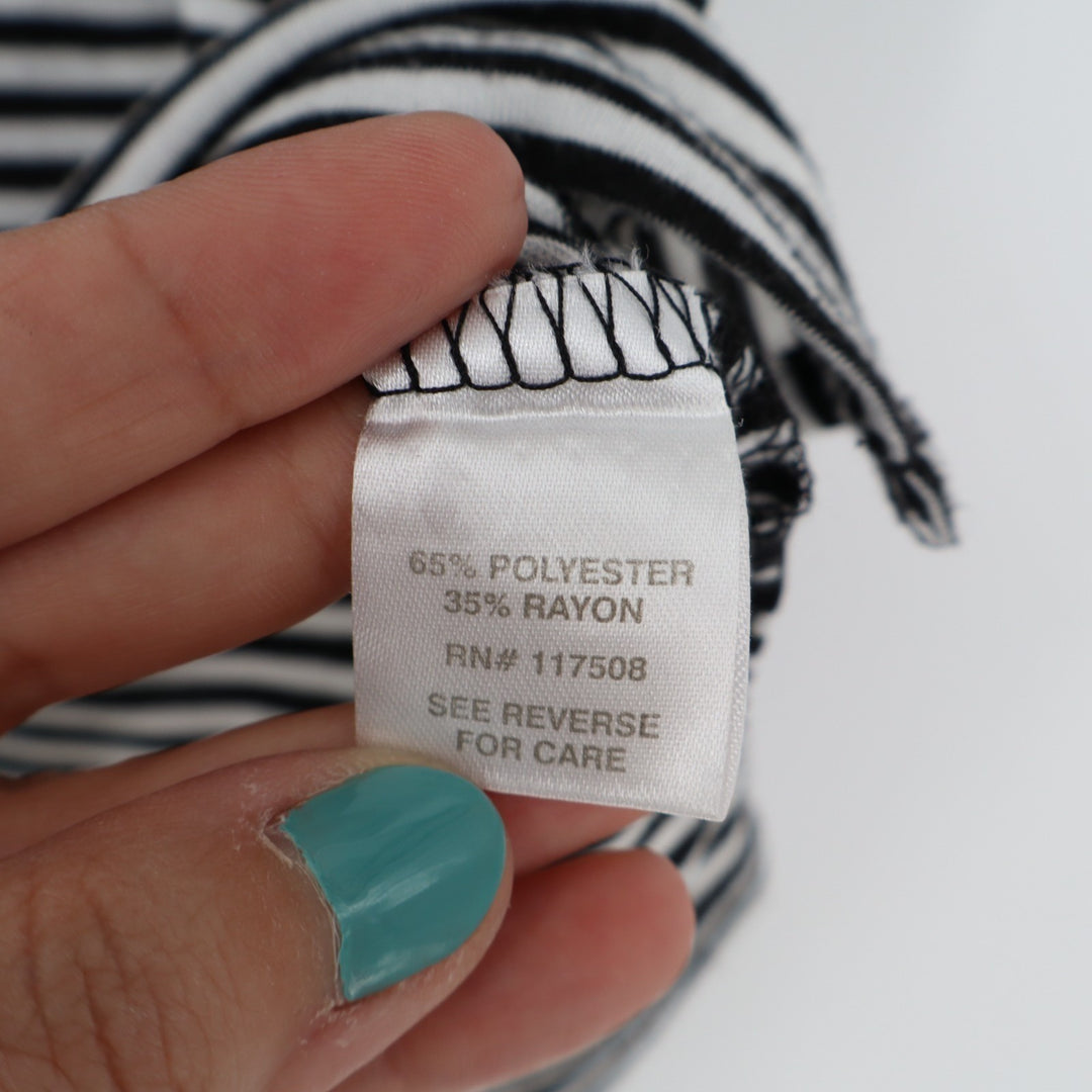 Clothing label with fabric composition details held by a hand against a striped background