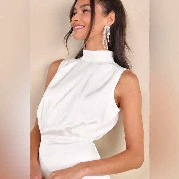 Woman wearing a white sleeveless top with a plain background