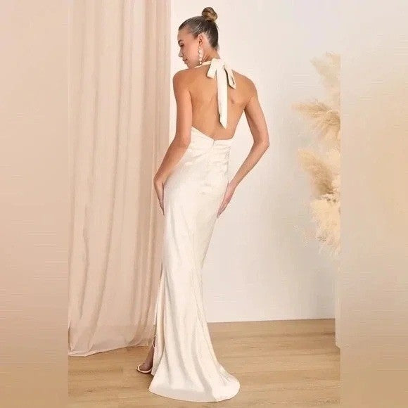 Woman in a white evening gown with a high slit, standing against a neutral background.